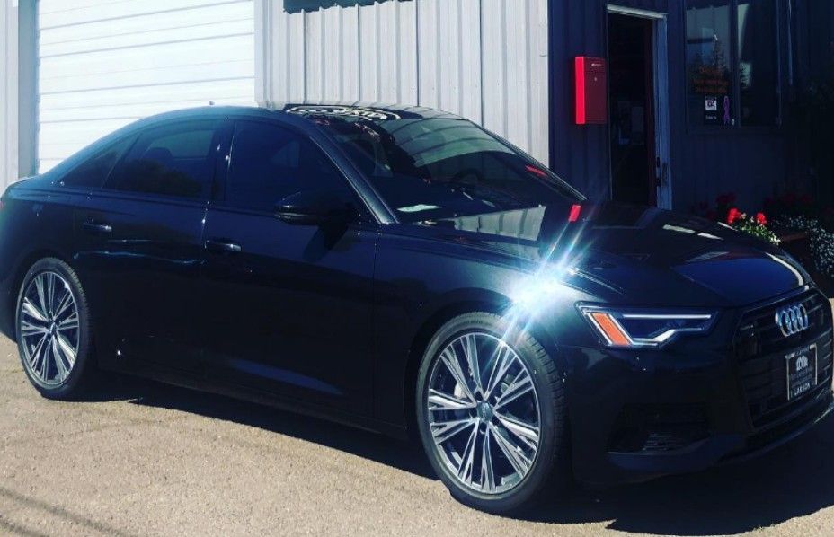 Black Audi sedan parked outside a building with tinted windows.