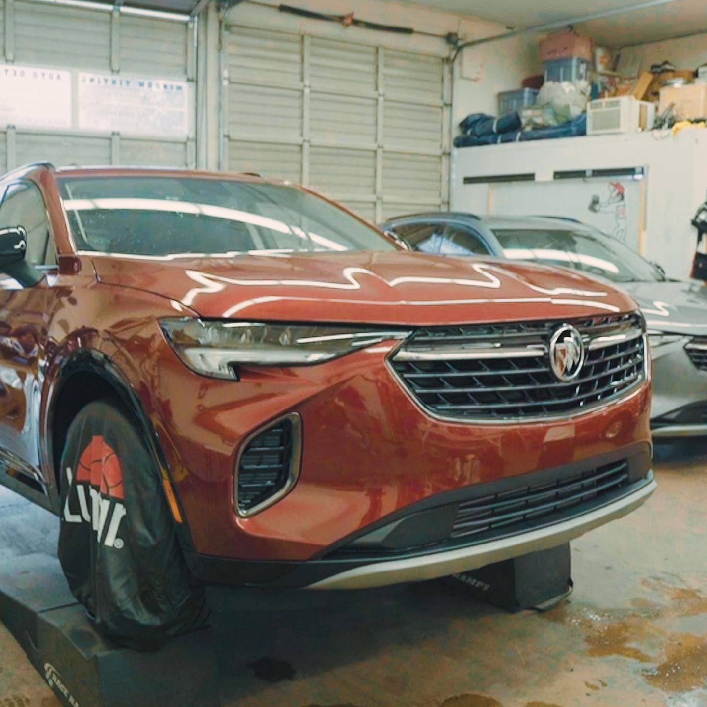 Orange Buick SUV parked in a garage, front view with hood open slightly.
