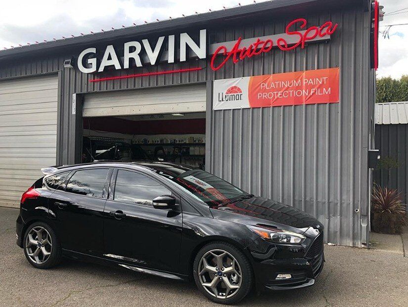 paint protection film on a black car in front of Garvin Auto Spa
