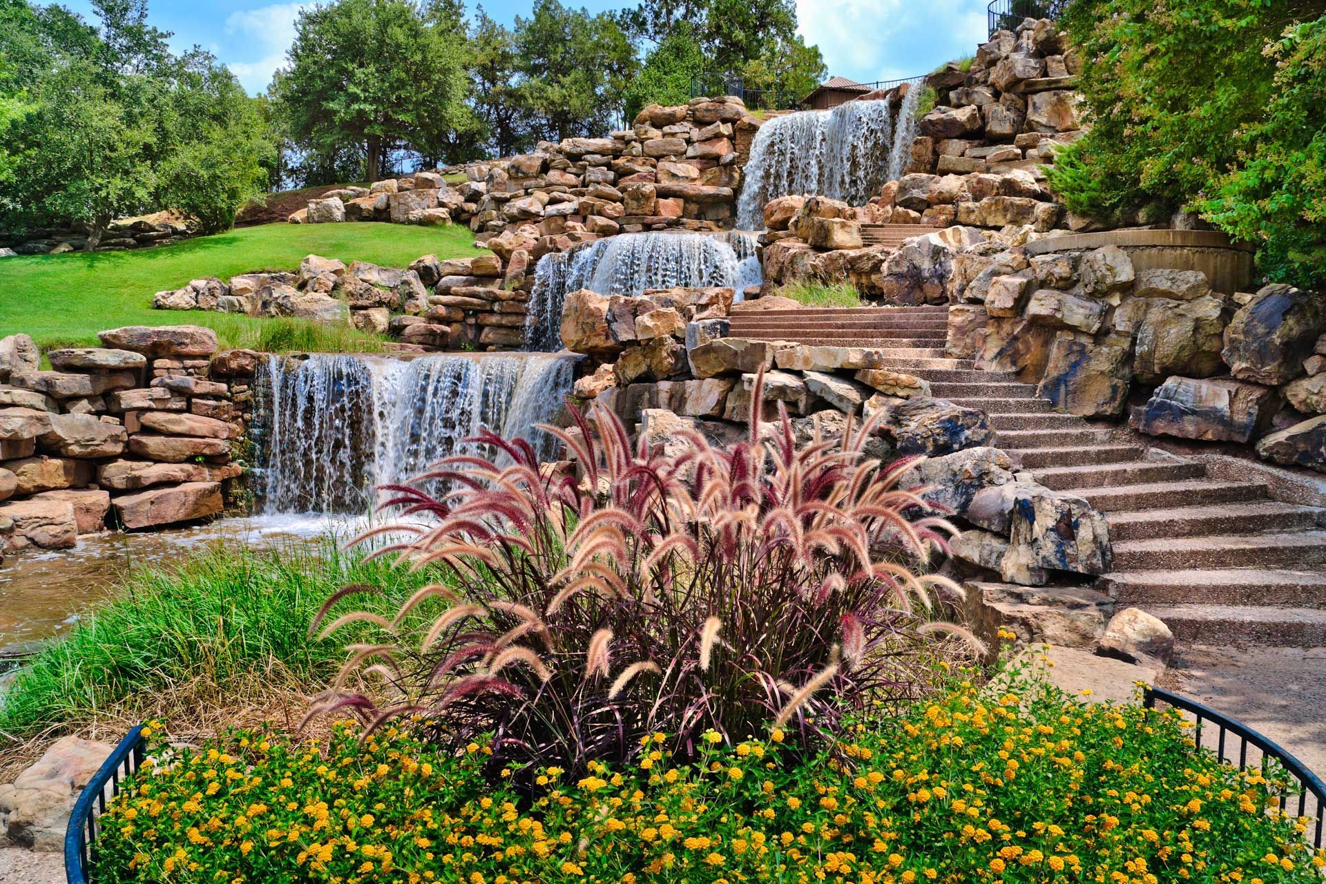 Waterfall cascading over layered rocks with steps and colorful plants.