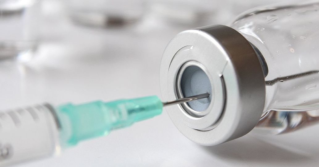 Syringe needle inserted into a vial, extracting medication.