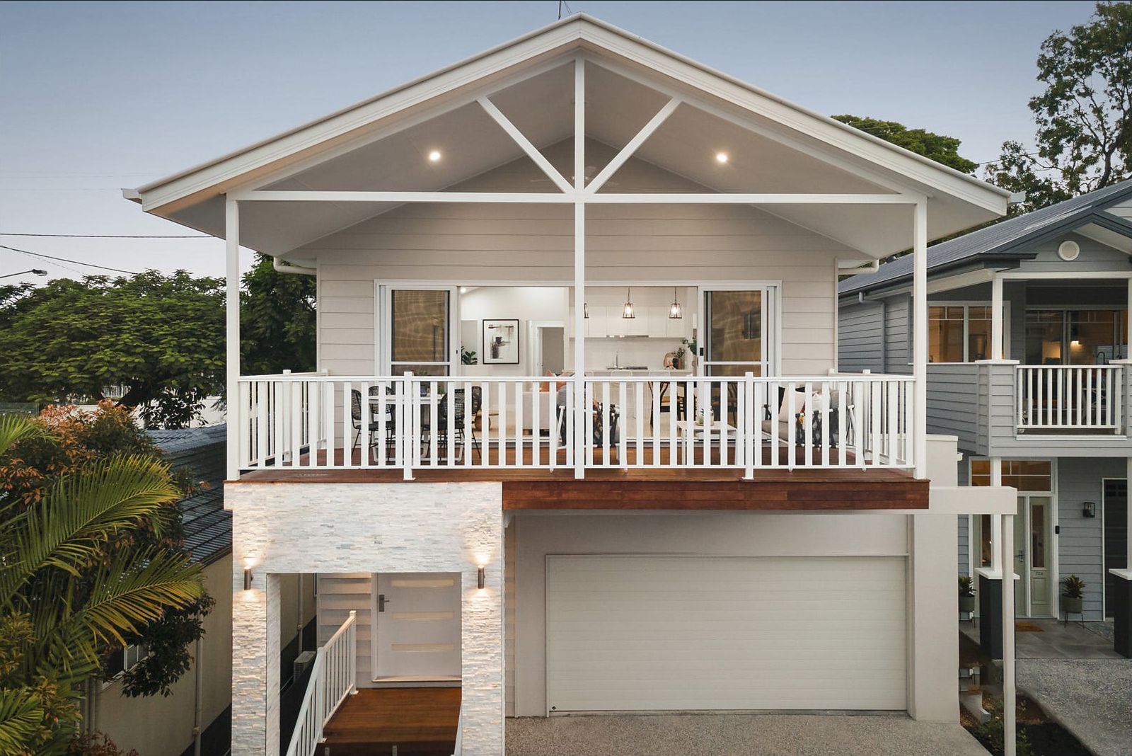 Two-story house with a white balcony and garage. The upper level has a balcony overlooking the street; the lower has a garage.