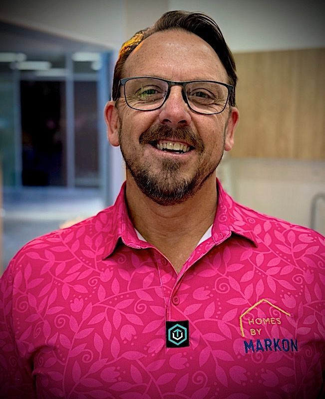Man with glasses smiles, wearing a pink floral polo shirt, Mark Uzzell