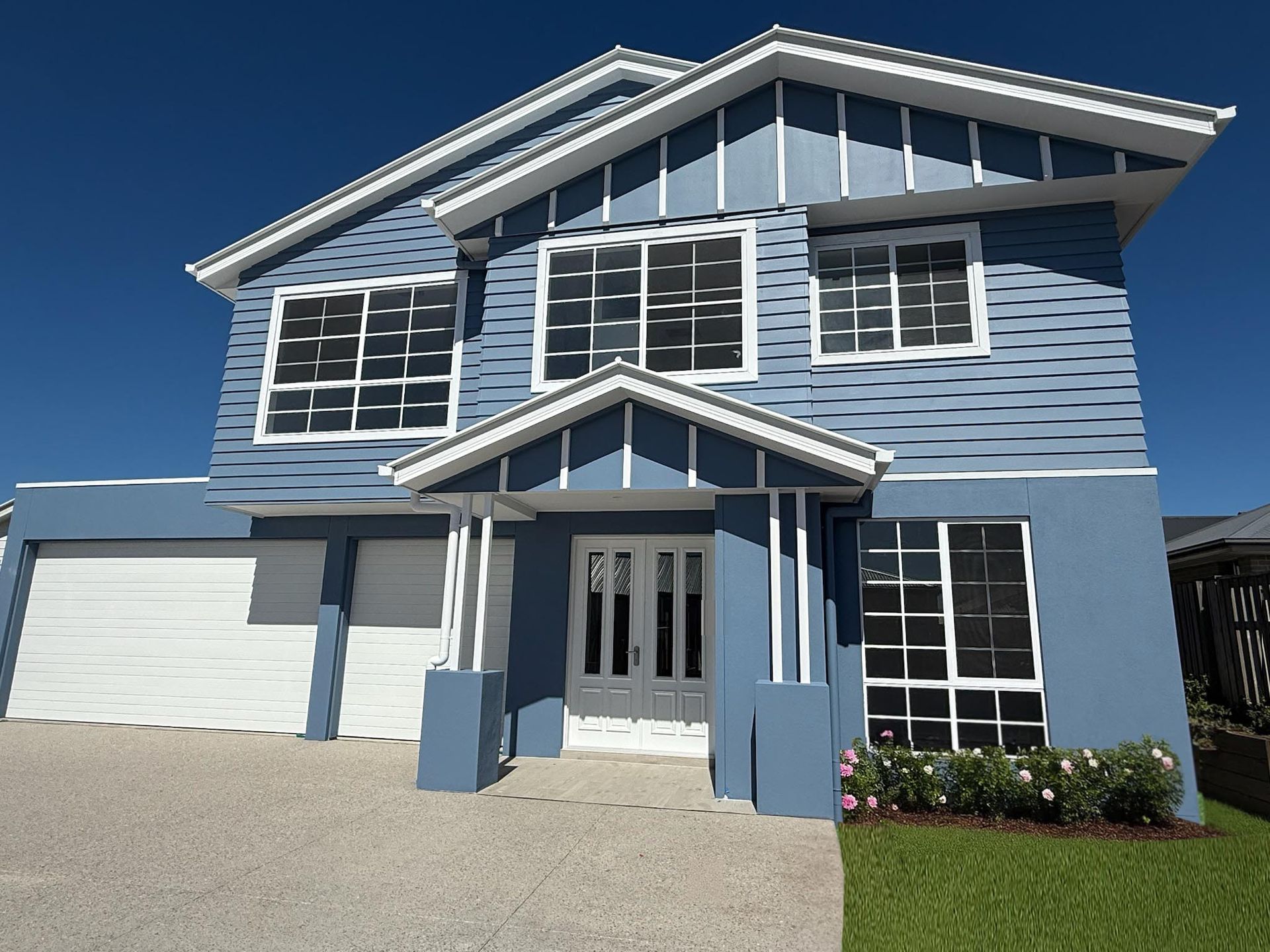 Modern two-story house with white exterior, black garage door, and wooden accents.