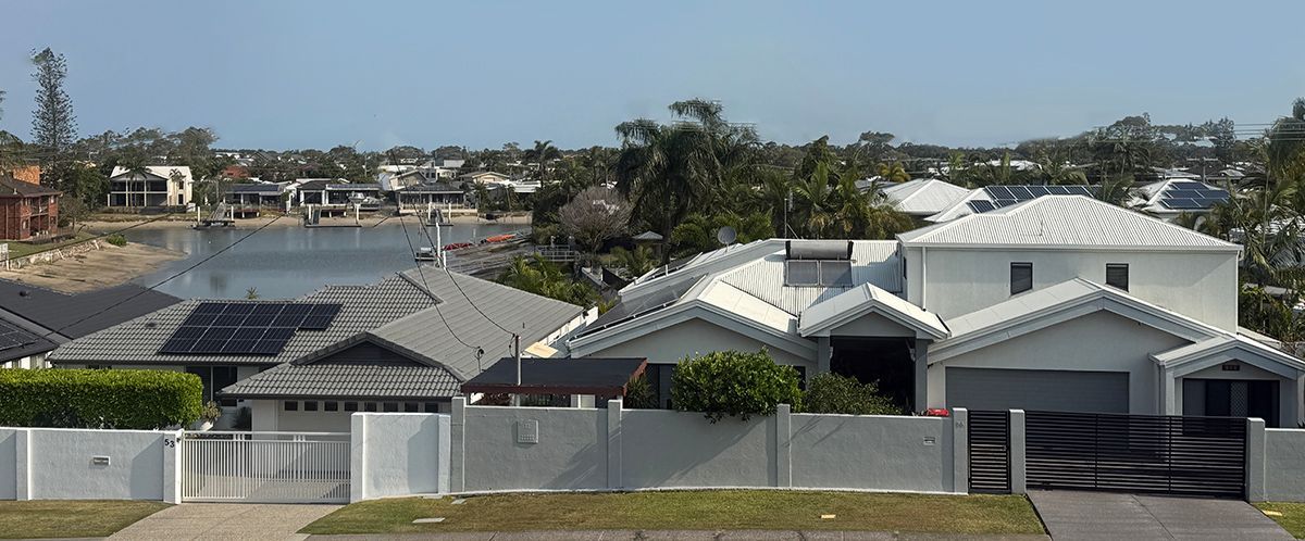 Houses with white walls and gray roofs are by a body of water.