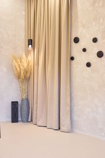 Beigefarbene minimalistische Ecke mit drapierten Vorhängen, schwarz gestreifter Vase