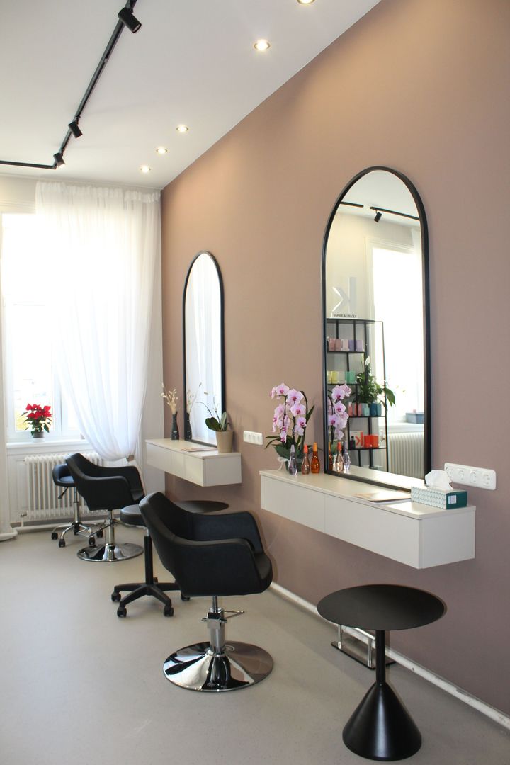 Modernes Saloninterieur mit Friseurstühlen, Spiegeln und einem Manikürtisch am Fenster