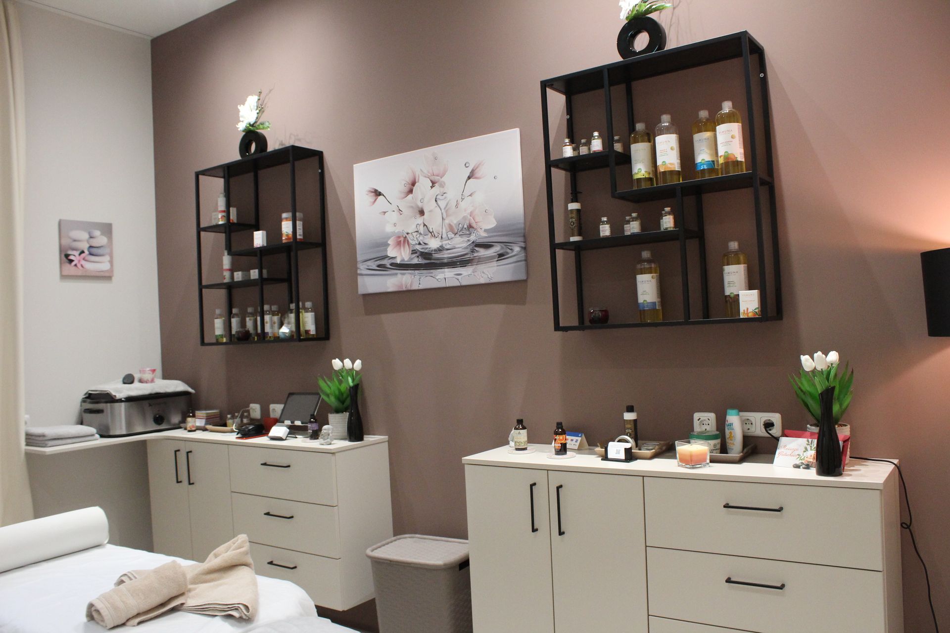 Spa-Behandlungsraum mit zwei Wandregalen, Schränken, Dekoration und einer Massageliege