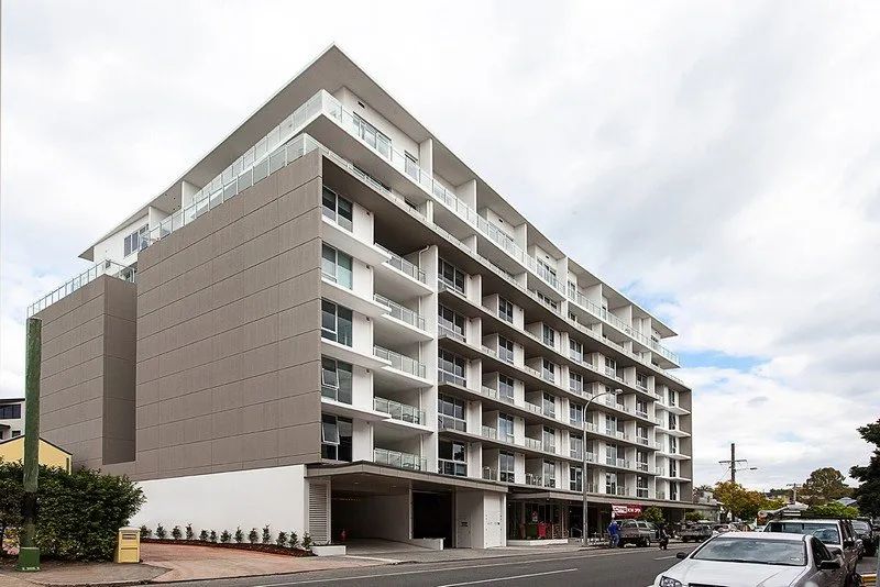 Modern multi-story apartment building with balconies and parked cars outside