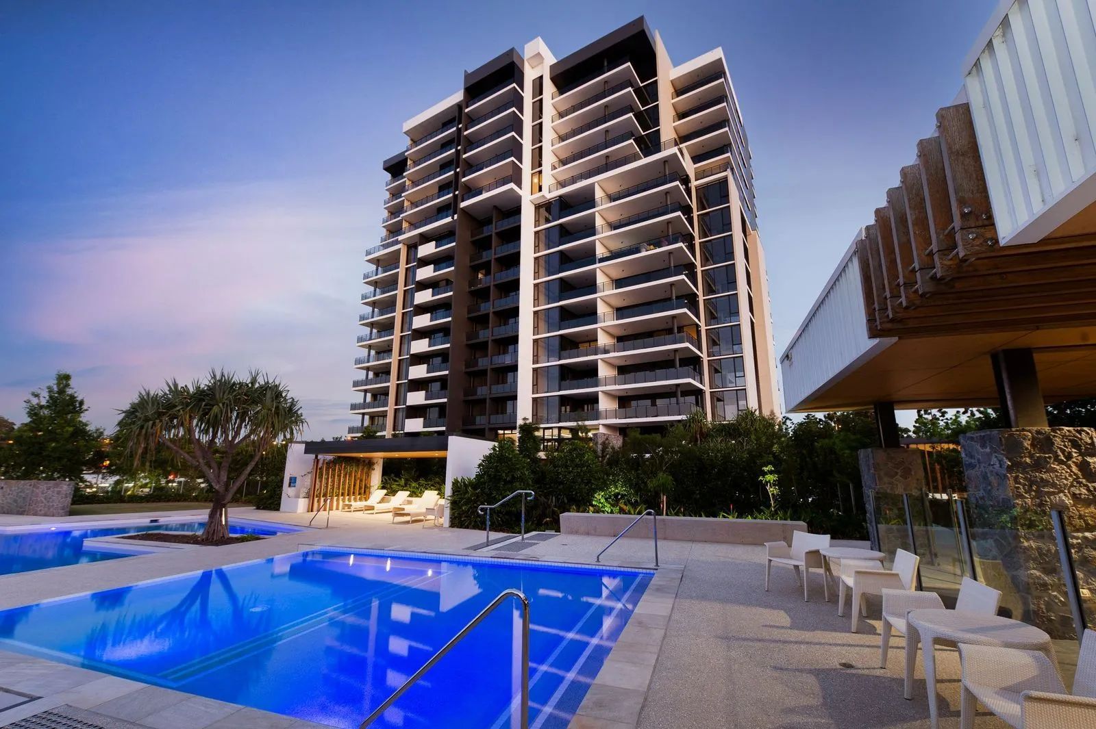 Modern high-rise hotel with rooftop pool and lounge chairs at dusk
