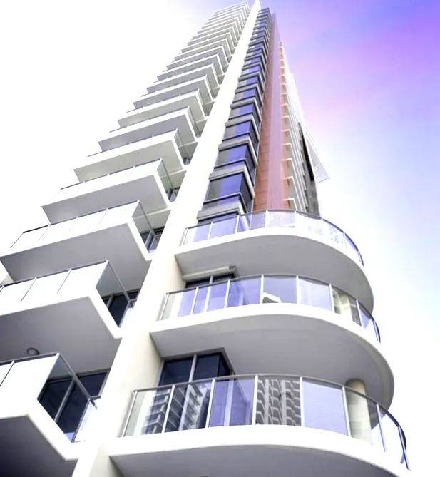 Low-angle view of a tall modern apartment building with white balconies against a blue-purple sky