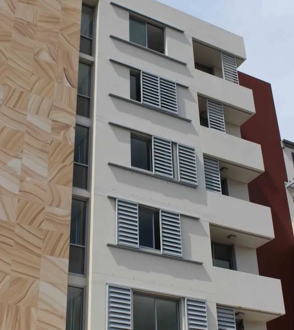 Modern apartment building facade with white and red exterior and shuttered windows