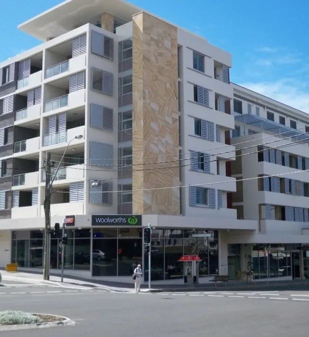 Modern apartment building with balconies and ground-floor shops at a street corner