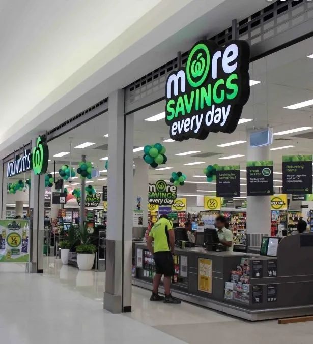 Pharmacy counter in a store with “more savings every day” signage and a customer in front