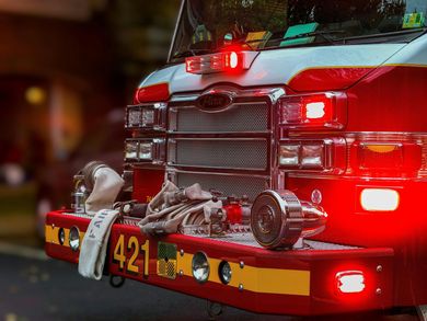 Fire truck with flashing red lights and damaged front bumper at night