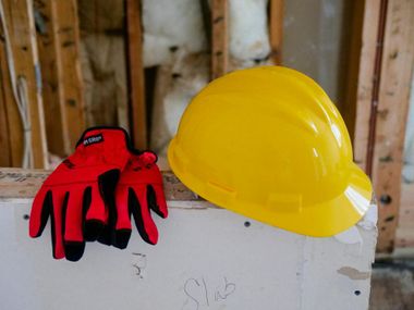 Red gloves and yellow hard hat on a ledge in an unfinished construction area