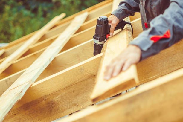 Carpenter using a drill on wooden rafters, outdoors, natural light.