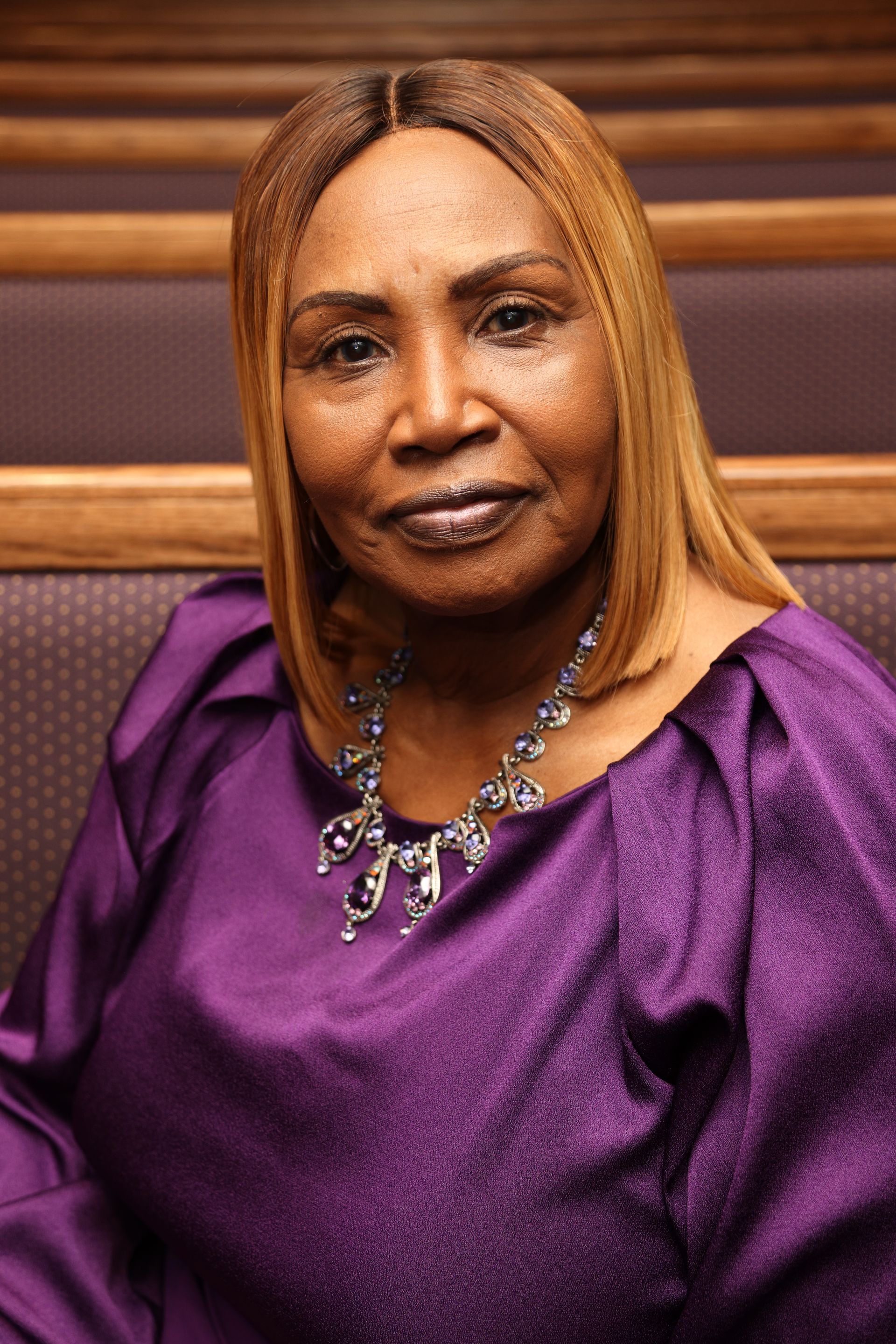 A woman is wearing a purple dress and a necklace.