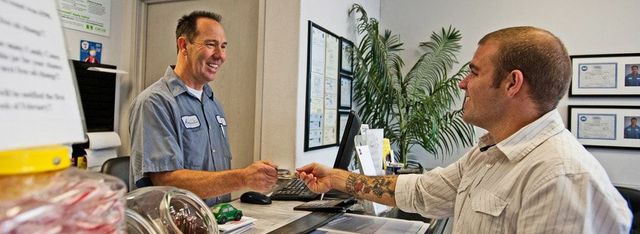 A man is giving a credit card to another man in a store.