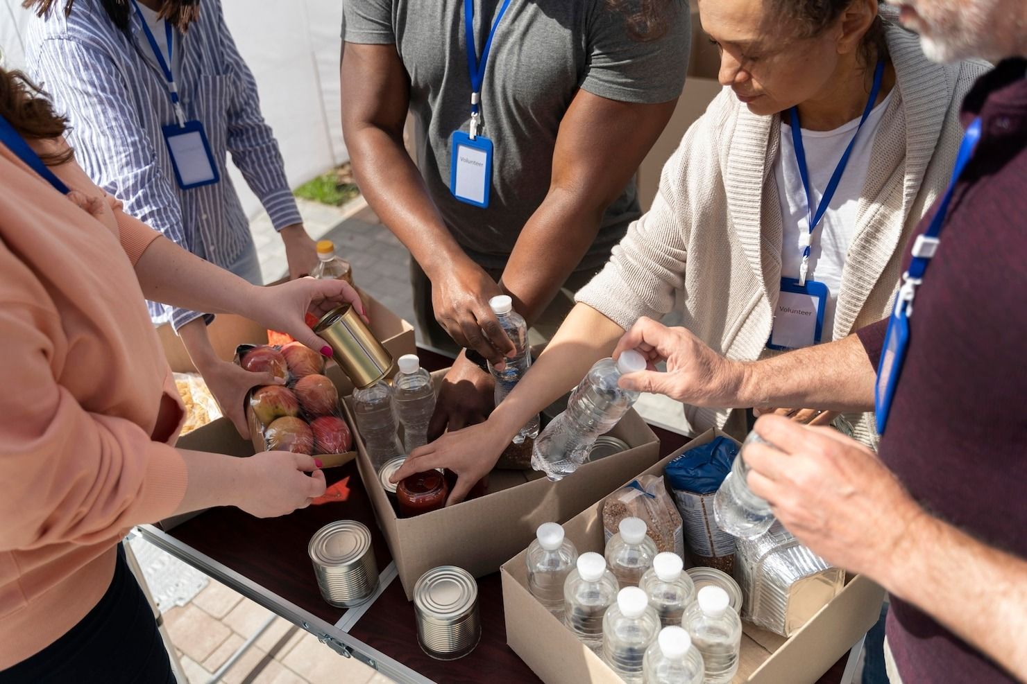 Volunteers work together to sort and pack food and water donations into cardboard boxes for distribution.