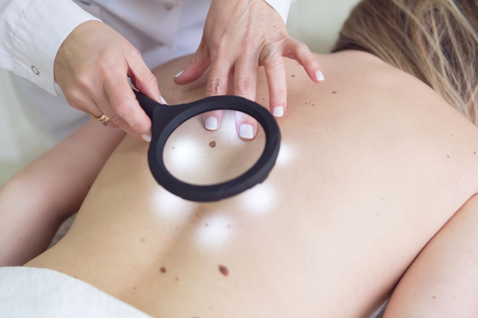 un medico sta esaminando la pelle di una donna con una lente d' ingrandimento .