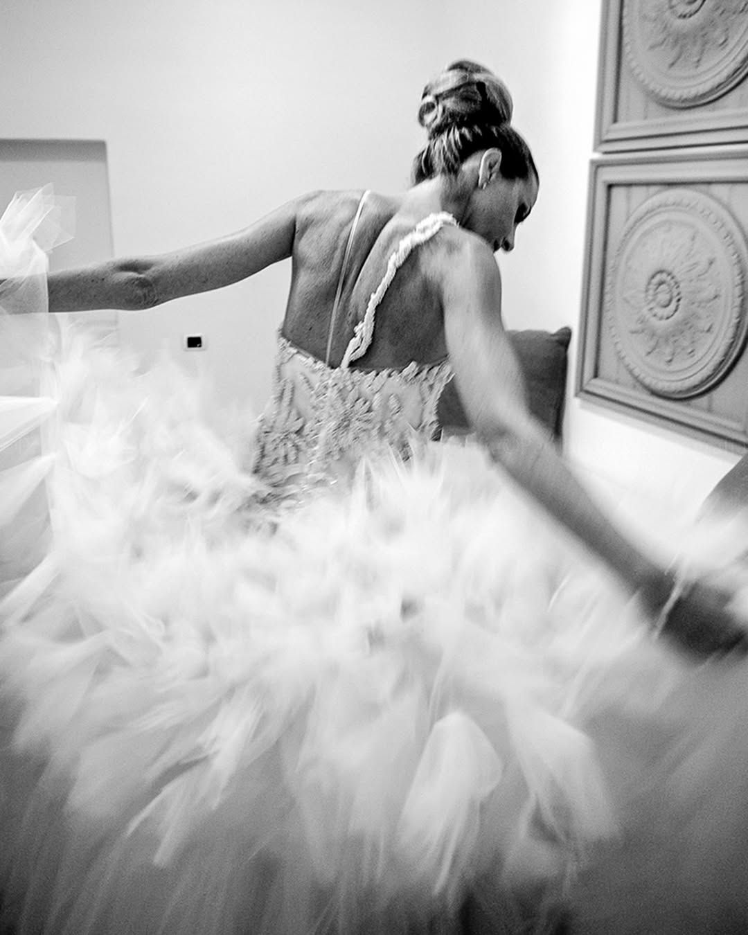 Ballerina in bianco e nero con un abito svolazzante, immortalata a metà di una piroetta su un palcoscenico.