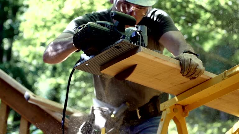 Carpenter cutting a wood beam with a circular saw.