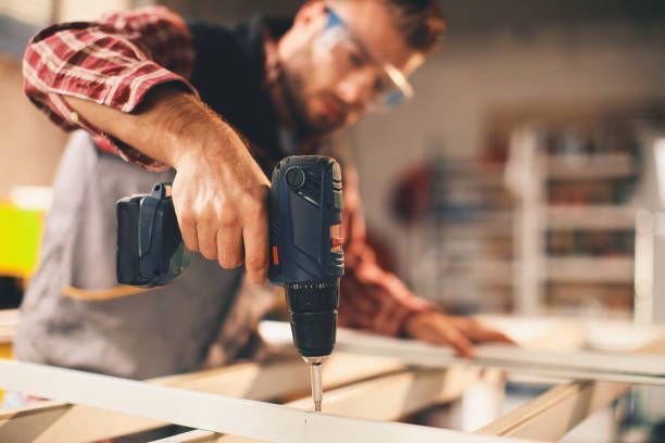 Carpenter using a cordless drill on a wood project.