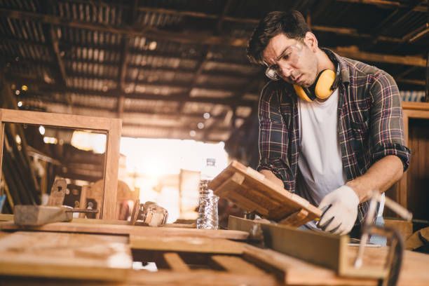 Woodworker measuring and inspecting wood in a shop