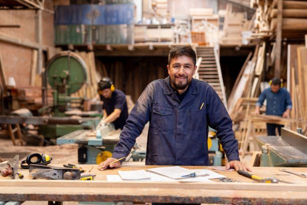 Smiling male carpenter standing at a workshop table.