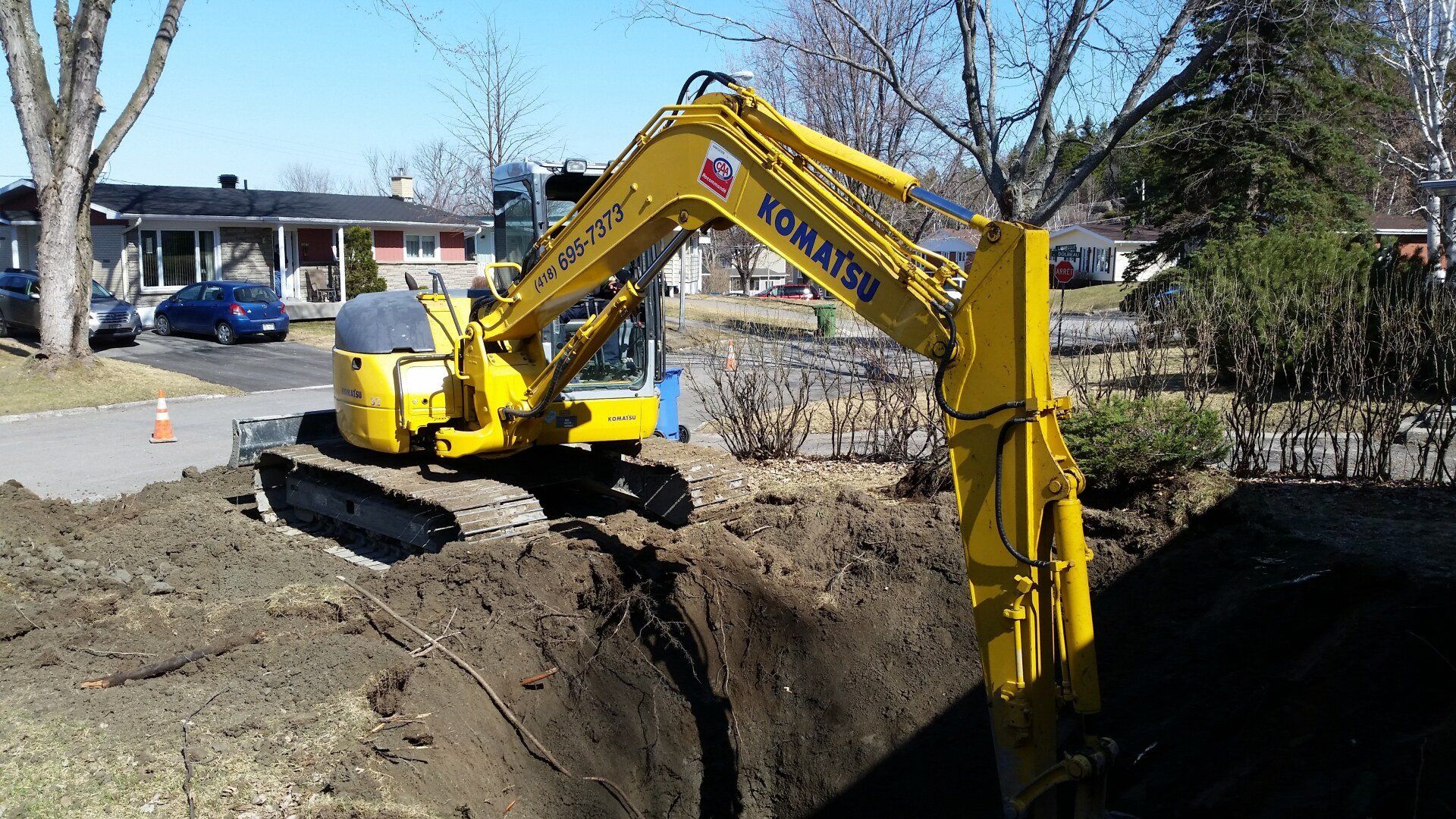 Une excavatrice jaune creuse un trou dans le sol.