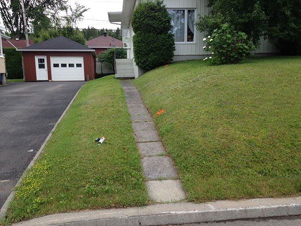 Un trottoir menant à une maison avec un garage en arrière-plan
