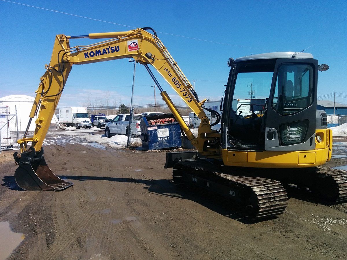 Une excavatrice Komatsu jaune est garée sur un terrain en terre