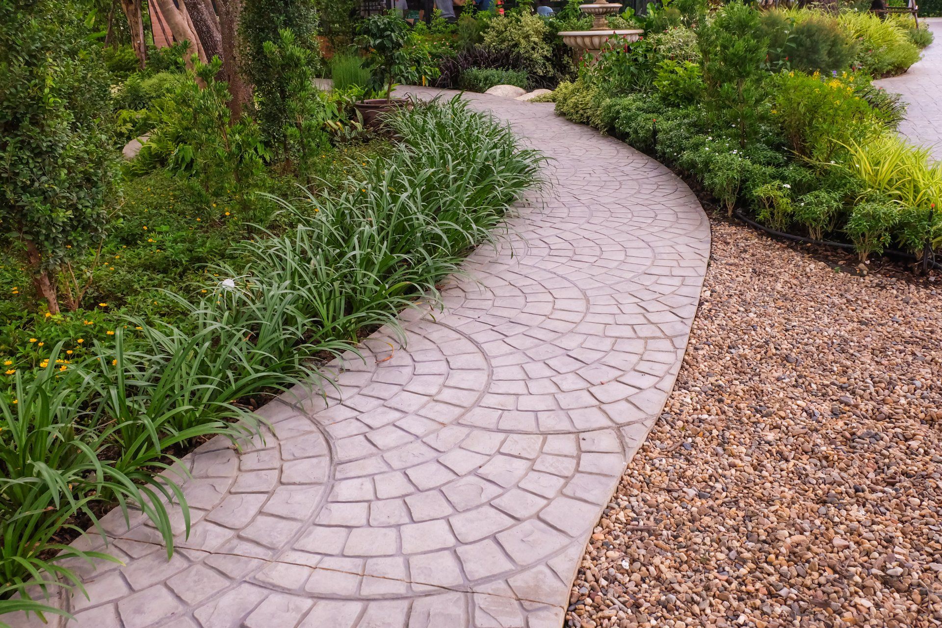 Une allée en briques dans un jardin entouré de plantes et de gravier.