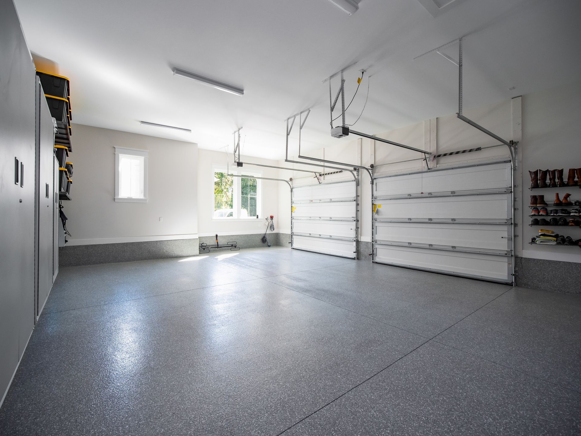 A large empty garage with two garage doors open.