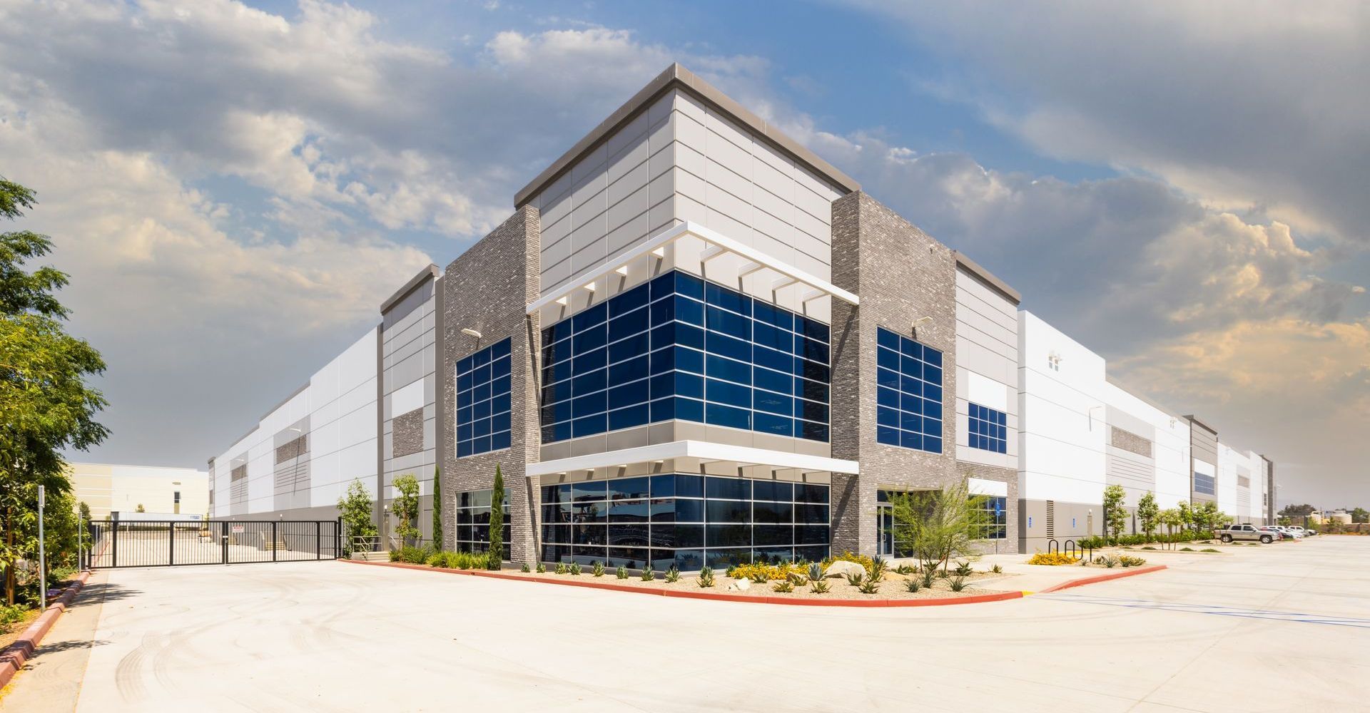 A large warehouse building with a lot of windows and a lot of trees in front of it.