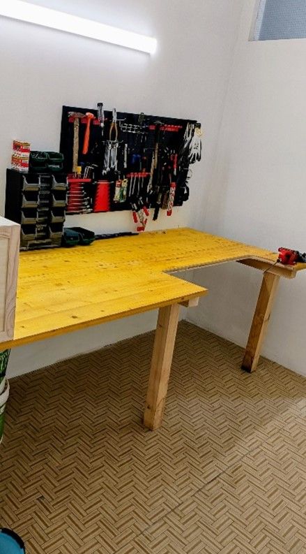 In una piccola officina, un banco da lavoro in legno con attrezzi appesi a una parete.