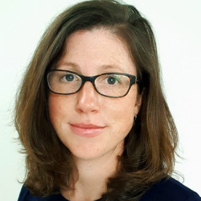 Portrait of a woman with shoulder-length brown hair and glasses against a white background