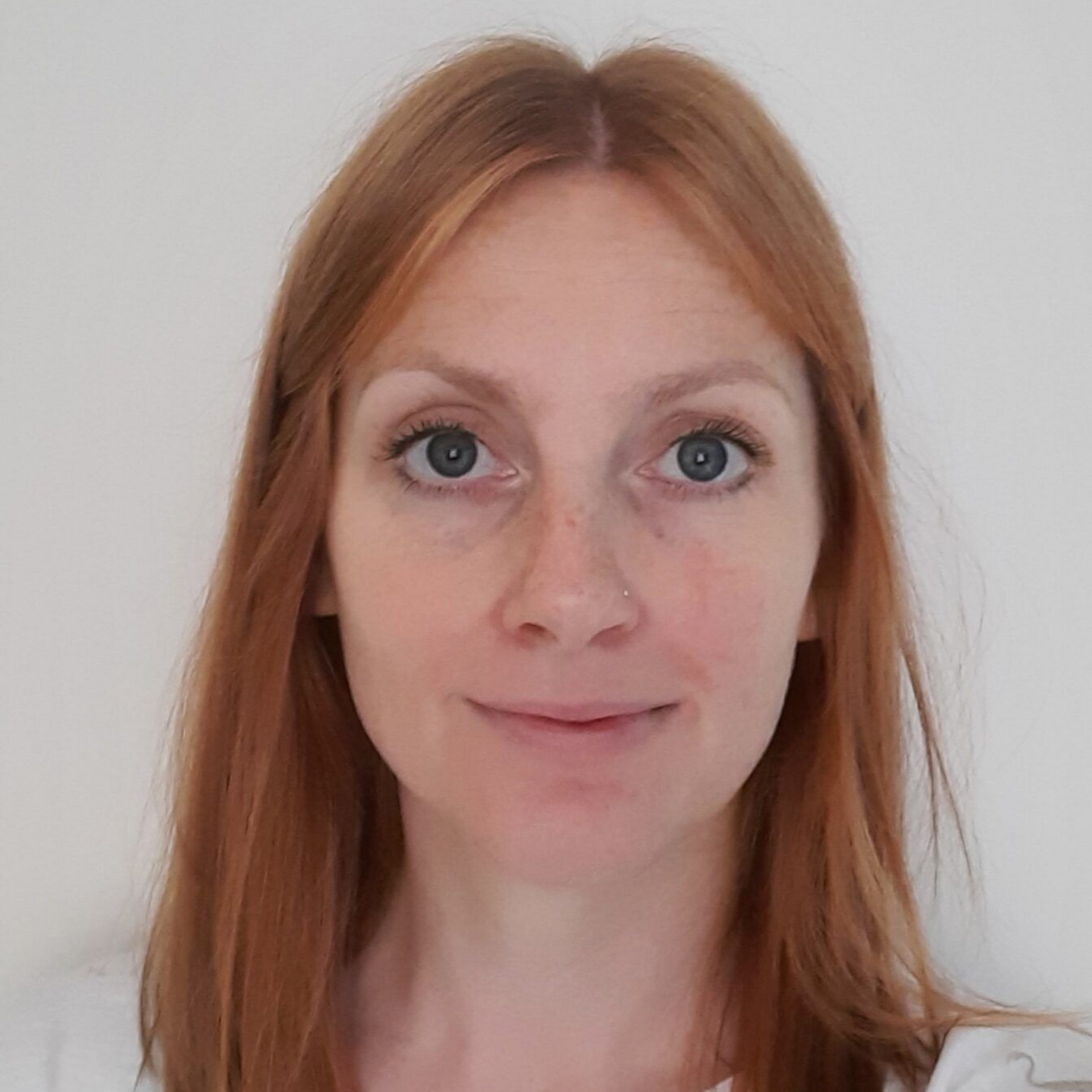 Portrait of a red-haired person smiling against a plain light background