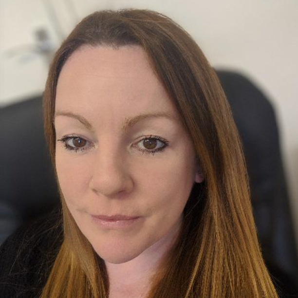 Close-up portrait of a woman with long brown hair and a neutral expression indoors
