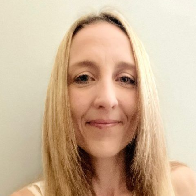Close-up of a smiling woman with long blonde hair against a plain light background