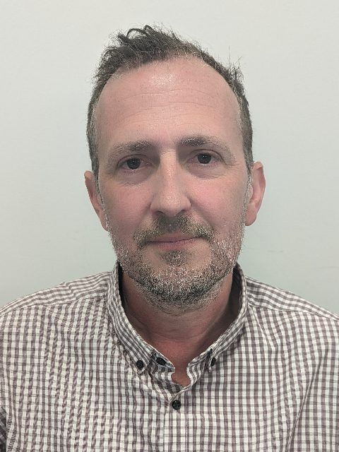 Portrait of a man in a checkered shirt against a plain light background