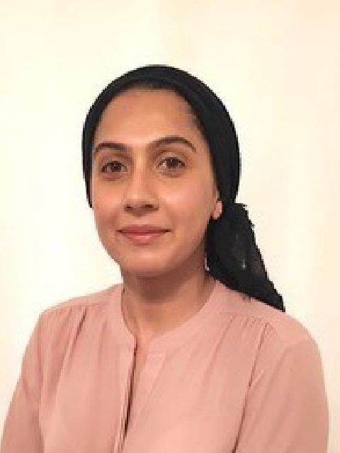 Portrait of a smiling person in a pink top against a plain light background