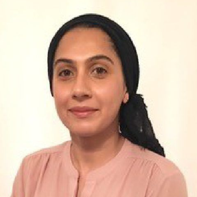Portrait of a woman with dark hair, wearing a pale pink blouse against a light background