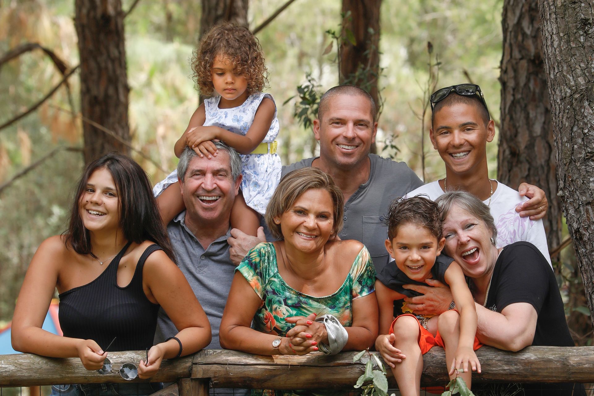 A large family is posing for a picture in the woods.