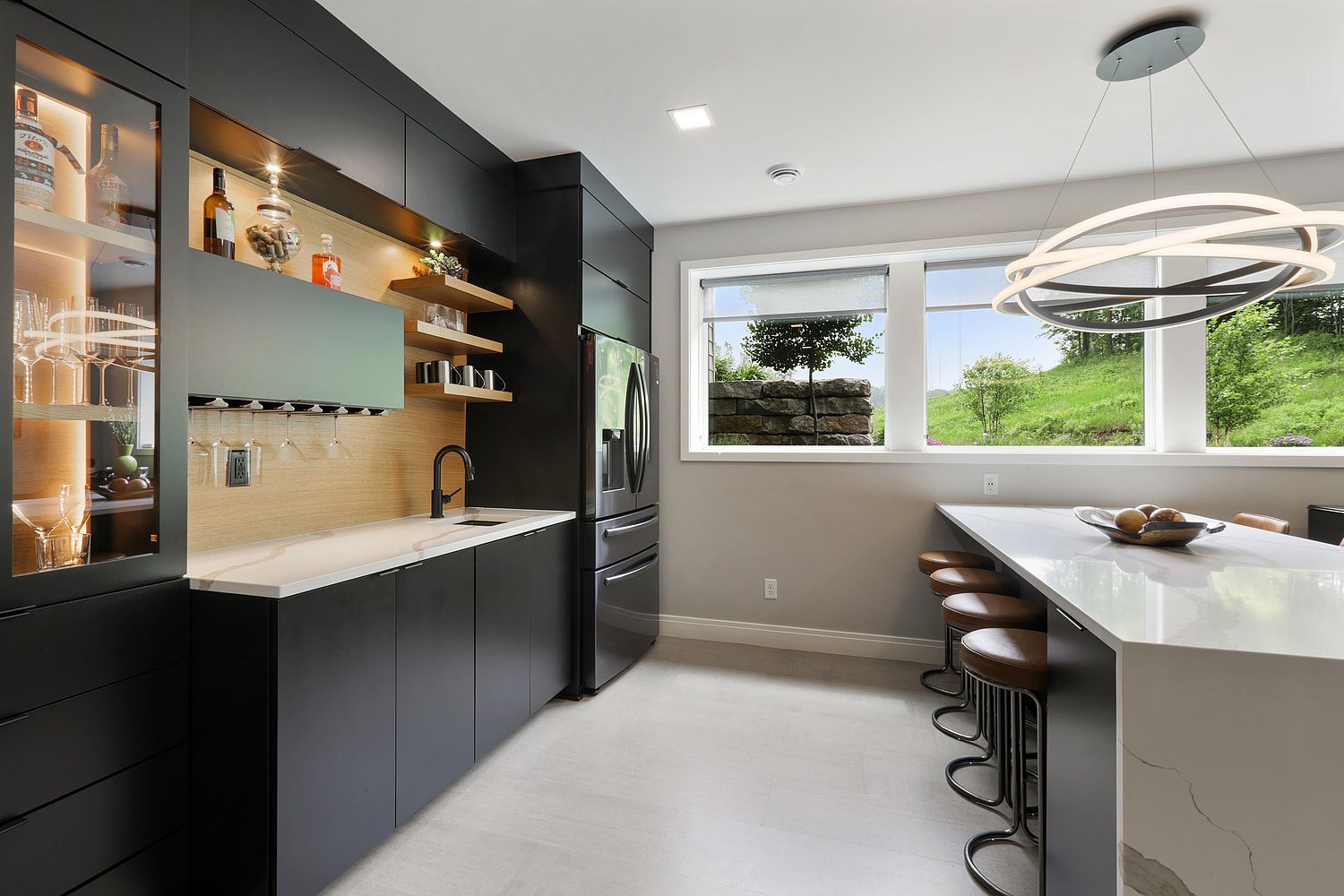 Modern black kitchen with a bar area, marble countertops, and a large island with seating.