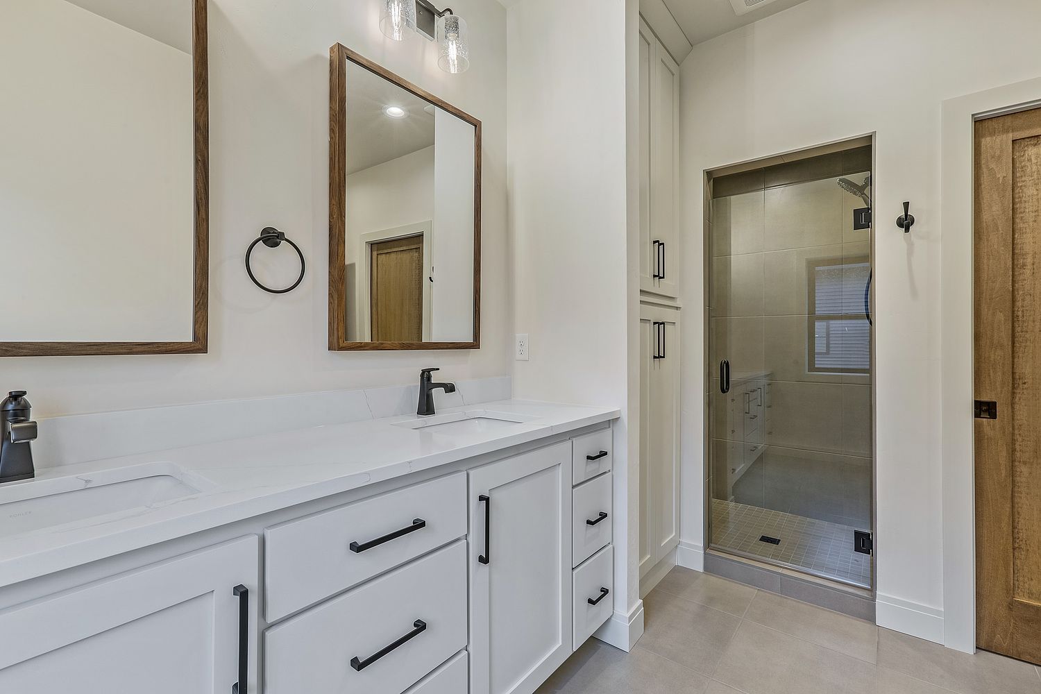 A bathroom with two sinks , a mirror and a walk in shower.