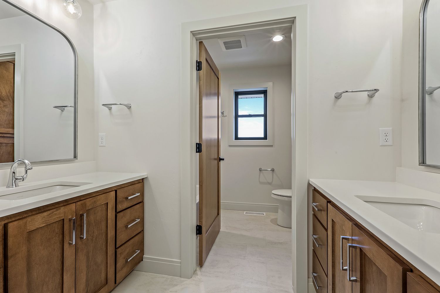 A bathroom with two sinks , a toilet , and a mirror.