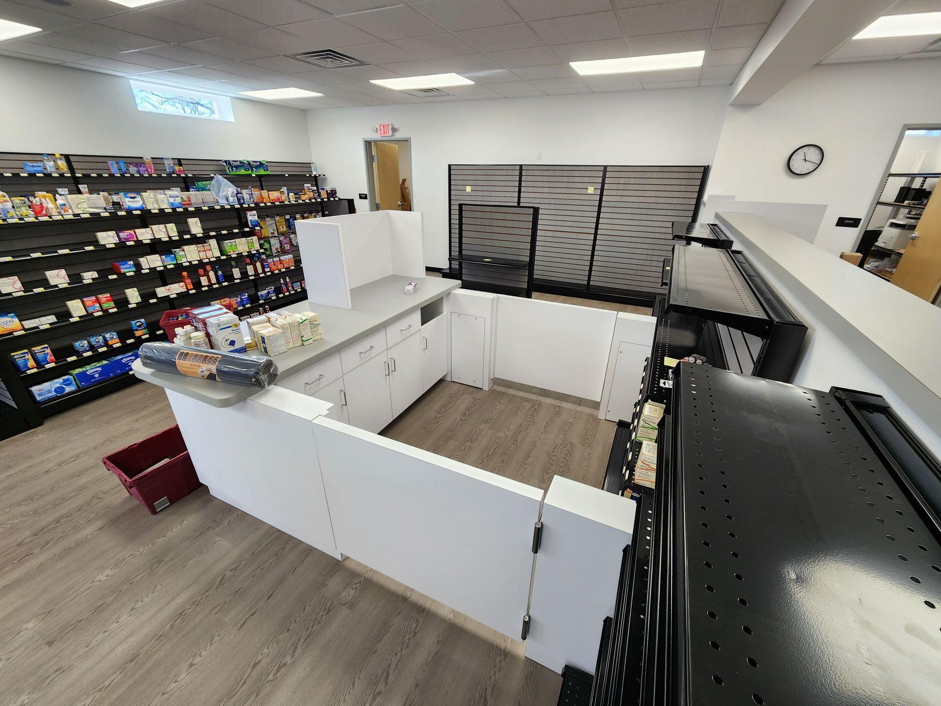 Interior shot of a store with shelves of products, a white counter, and a red bin.