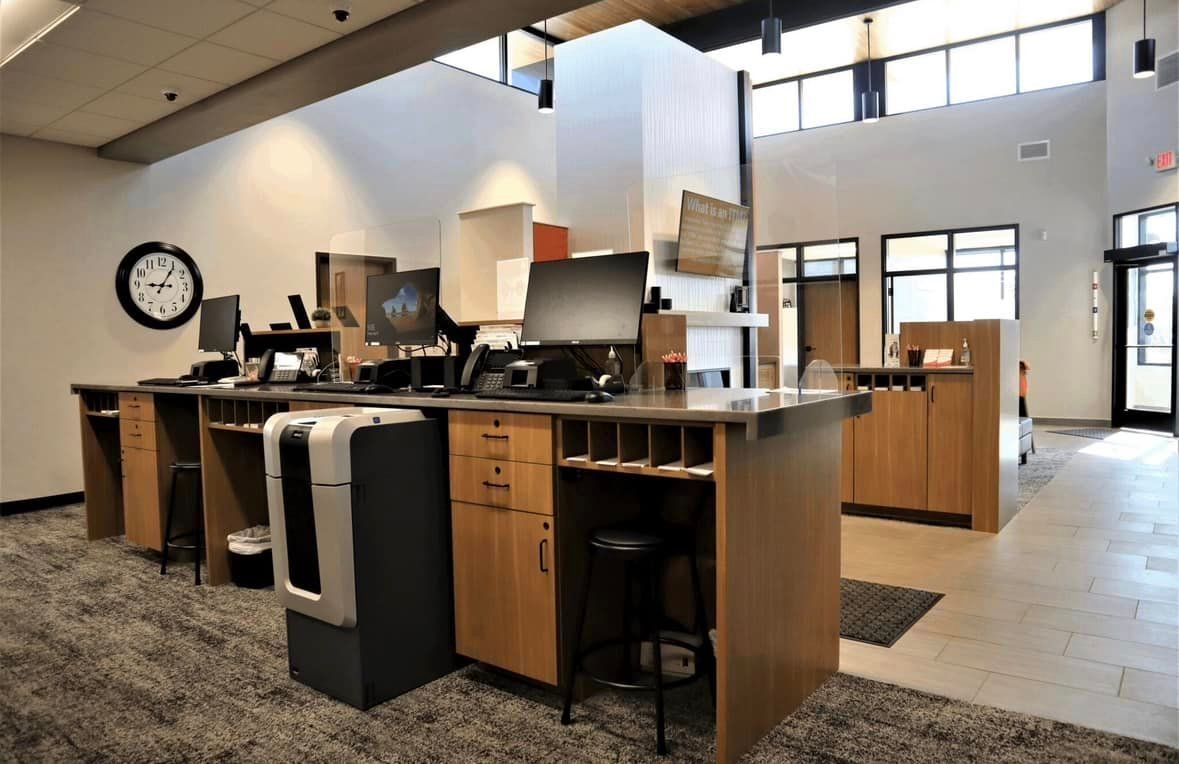 A room with a clock on the wall and a desk with a computer on it.